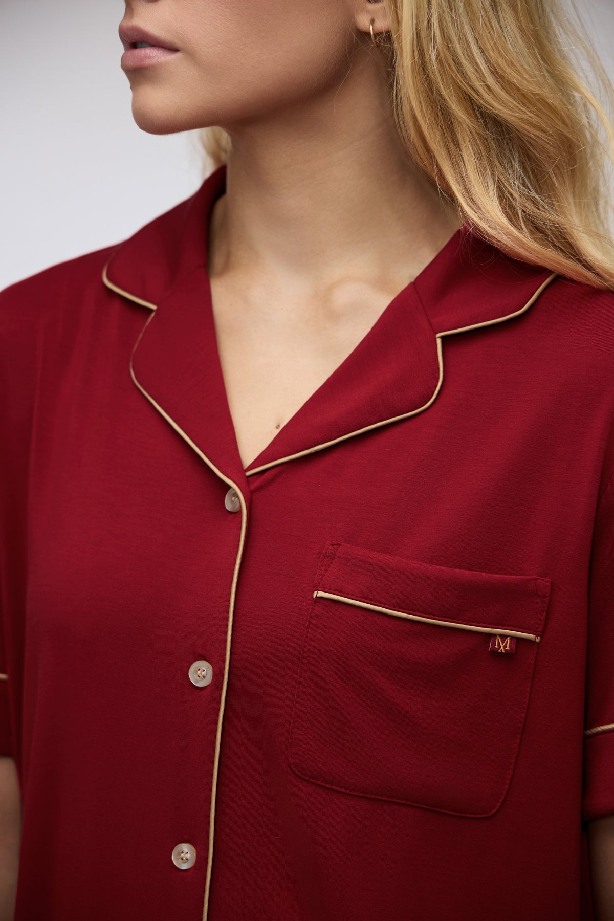 Close-up of the Moon & Mare Ember Set in wine, showing the neckline, champagne piping, buttons, and chest pocket.