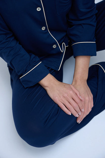 Seated detail view of the Moon & Mare Nocturne Set in navy, showing the soft drape and champagne piping.